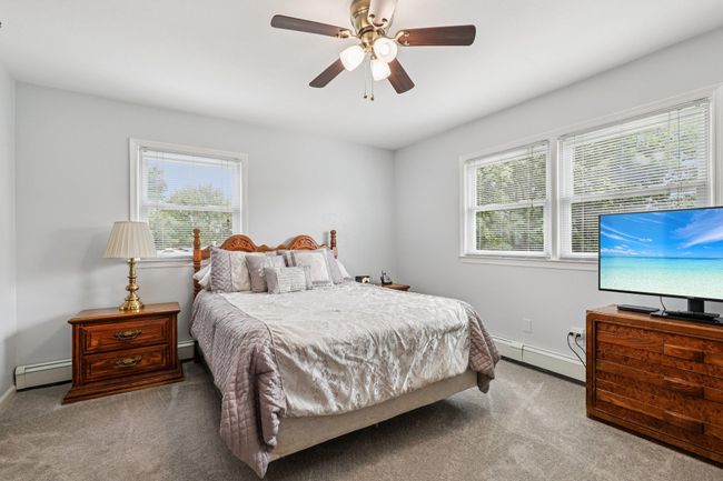 Carpeted bedroom featuring a baseboard heating unit and ceiling fan | Image 11