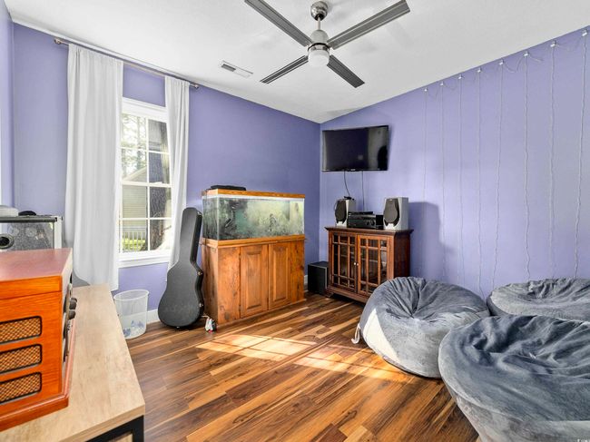 Bedroom featuring a ceiling fan, vaulted ceiling, wood finished floors, and visible vents | Image 22