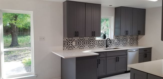 Kitchen featuring dishwasher, a sink, decorative backsplash, light countertops, and light marble finish floors | Image 7