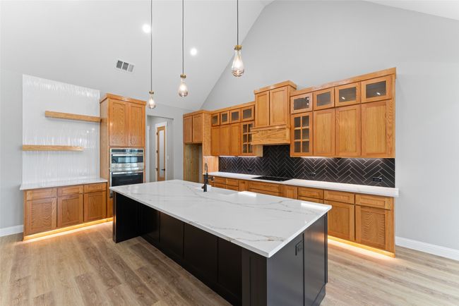 Kitchen featuring open shelves, light wood-style floors, double oven, decorative backsplash, and visible vents | Image 10