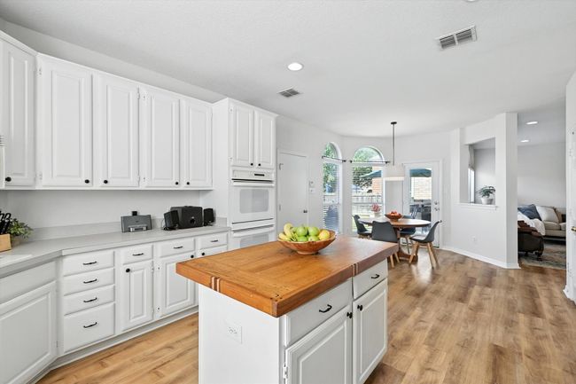 Kitchen featuring light wood finished floors, white cabinets, a kitchen island, decorative light fixtures, and recessed lighting | Image 15