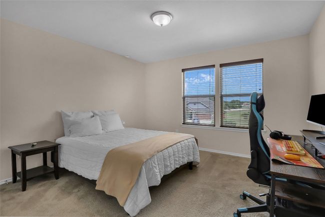 Bedroom with light colored carpet, baseboards, and a desk | Image 22