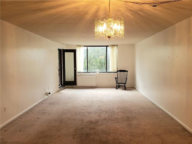 Carpeted spare room with an inviting chandelier | Image 7