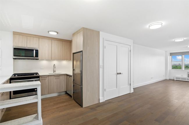 Kitchen with appliances with stainless steel finishes, light brown cabinets, light countertops, dark wood finished floors, and modern cabinets | Image 13
