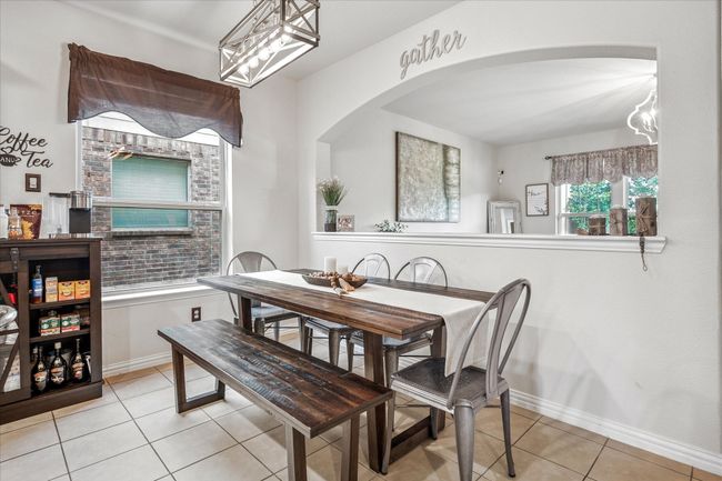 Dining room featuring light tile patterned floors, baseboards, arched walkways, and a chandelier | Image 8