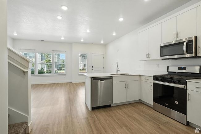 Kitchen with appliances with stainless steel finishes, light wood-style flooring, a peninsula, recessed lighting, and white cabinetry | Image 6