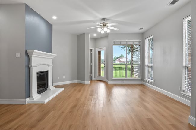Unfurnished living room featuring light wood-style flooring, baseboards, a ceiling fan, a glass covered fireplace, and recessed lighting | Image 17