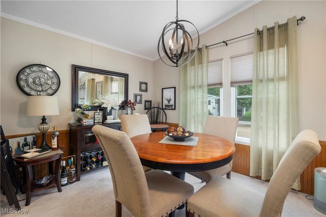 Dining space with light colored carpet, crown molding, and a chandelier | Image 20
