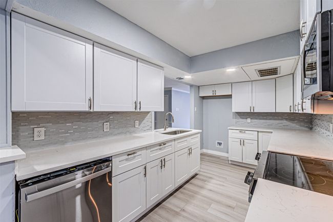Kitchen with white cabinetry, dishwasher, sink, and backsplash | Image 17