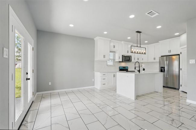Kitchen with decorative backsplash, appliances with stainless steel finishes, light countertops, and a healthy amount of sunlight | Image 5