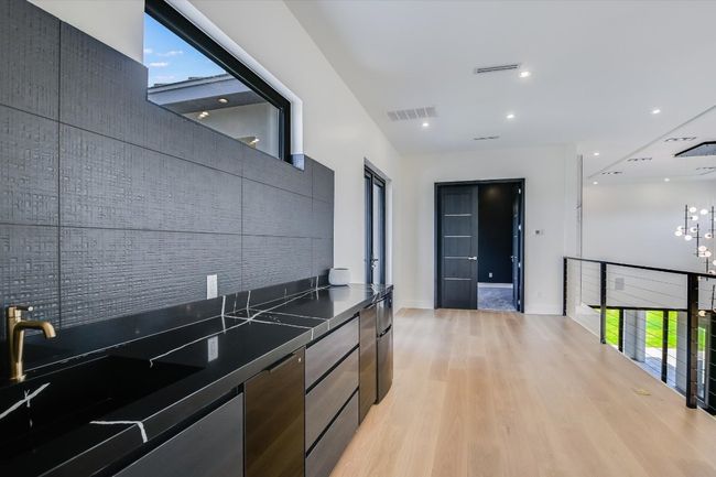 sink and serving area upstairs near media room with modern cabinets, dark countertops, plenty of natural light, and light wood-style flooring | Image 22