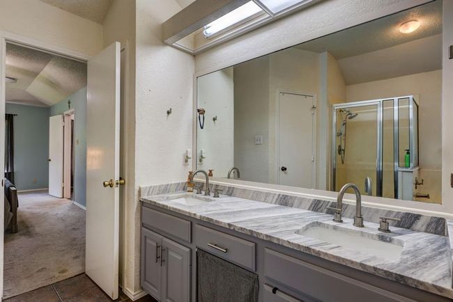 Bathroom featuring a stall shower, double vanity, a textured ceiling, and tile patterned floors | Image 8