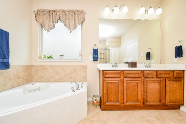 Bathroom includes a large soaking tub with modern fixtures, a neutral color palette, and ample lighting, creating a bright and inviting space. | Image 20