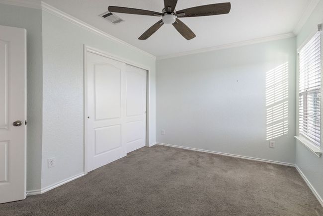Bedroom featuring crown molding, carpet flooring, a closet, a ceiling fan, and baseboards | Image 27