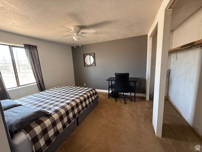 Carpeted bedroom with a textured ceiling, a ceiling fan, and a desk | Image 10