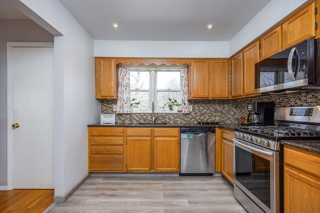 Kitchen featuring a sink, decorative backsplash, light wood-style floors, appliances with stainless steel finishes, and granite countertops | Image 5