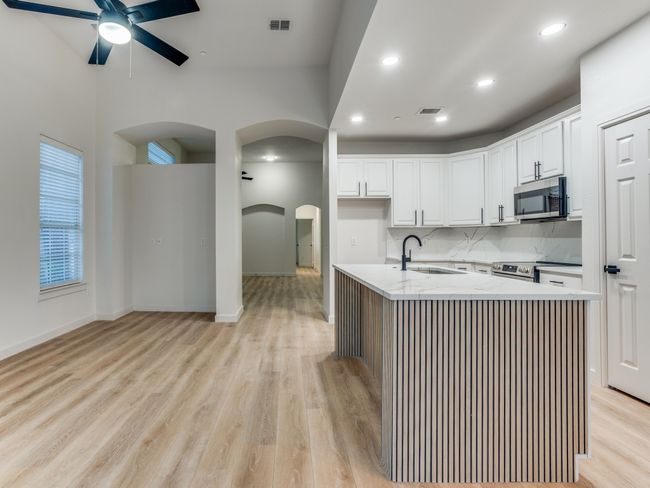 Kitchen with stainless steel appliances, arched walkways, a ceiling fan, light wood-style floors, and recessed lighting | Image 11