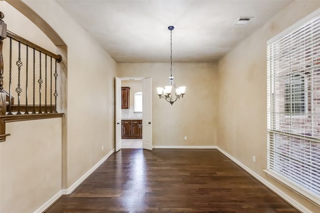 Unfurnished dining area featuring dark wood finished floors, a notable chandelier, and visible vents | Image 8