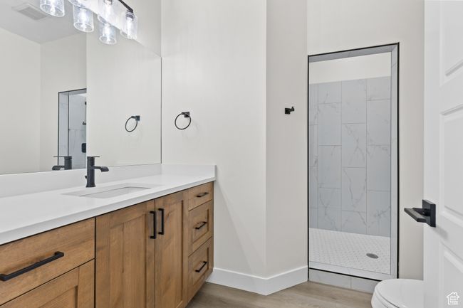 Full bath with visible vents, toilet, wood finished floors, vanity, and tiled shower | Image 34
