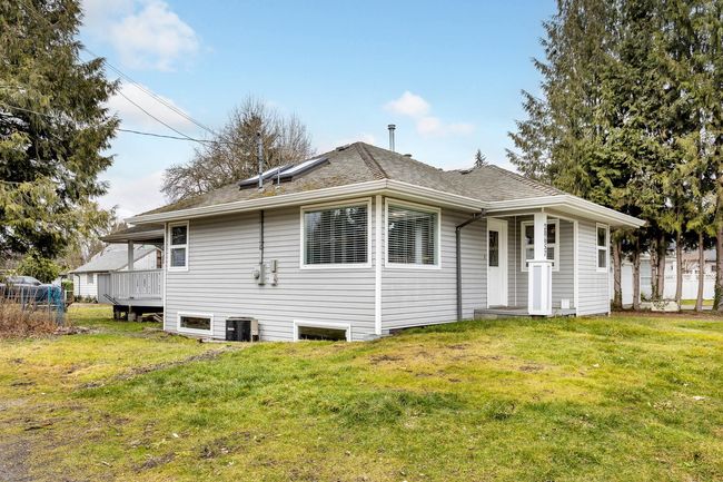 Rear view of house featuring a lawn, a shingled roof, and central AC unit | Image 14