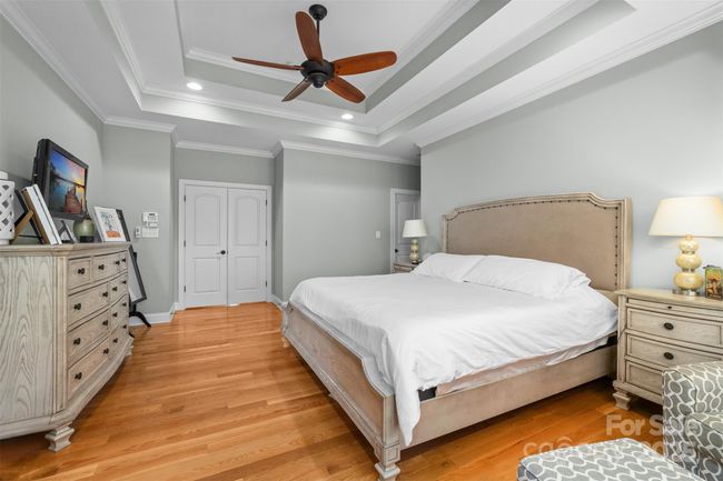 Primary ensuite on the main level offers tray ceiling, two walk-in closets, private access to deck and hardwood floors. | Image 17