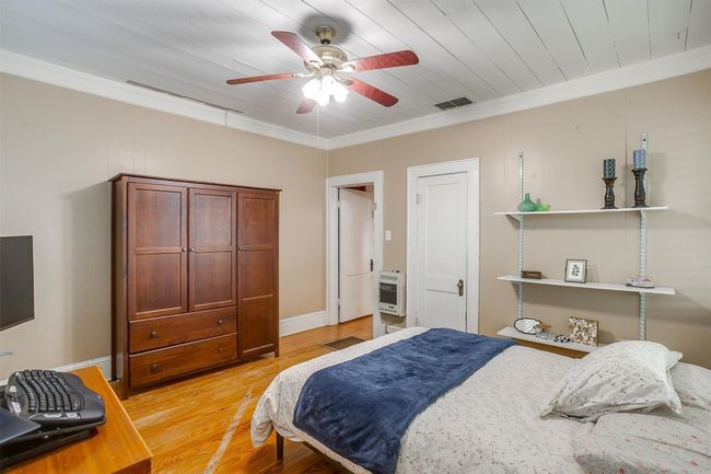 Bedroom with heating unit, light wood-style floors, ornamental molding, and a ceiling fan | Image 33