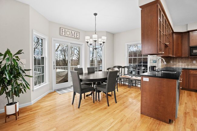 This bright eat-in kitchen offers wraparound windows and deck access, blending natural light and inviting warmth. | Image 7