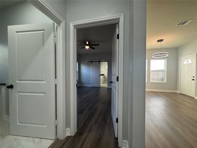 Corridor with a barn door and wood finished floors | Image 13