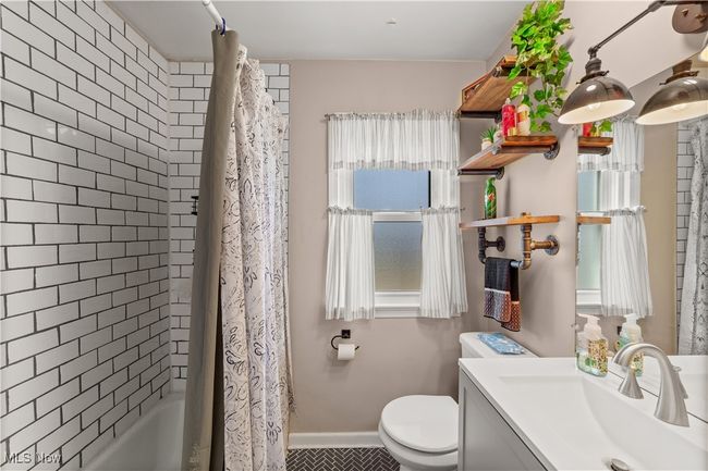 Full bath featuring toilet, tile patterned flooring, vanity, shower / tub combo with curtain, and baseboards | Image 8
