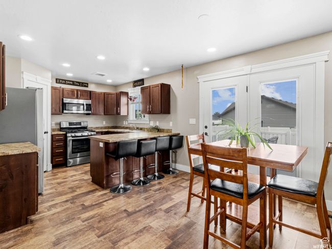 Kitchen with appliances with stainless steel finishes, light wood finished floors, recessed lighting, light countertops, and a breakfast bar | Image 4