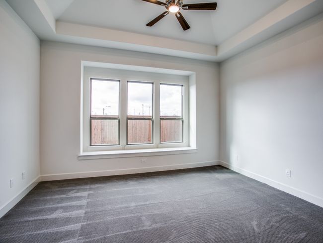 Unfurnished room with dark colored carpet, ceiling fan, and a tray ceiling | Image 13