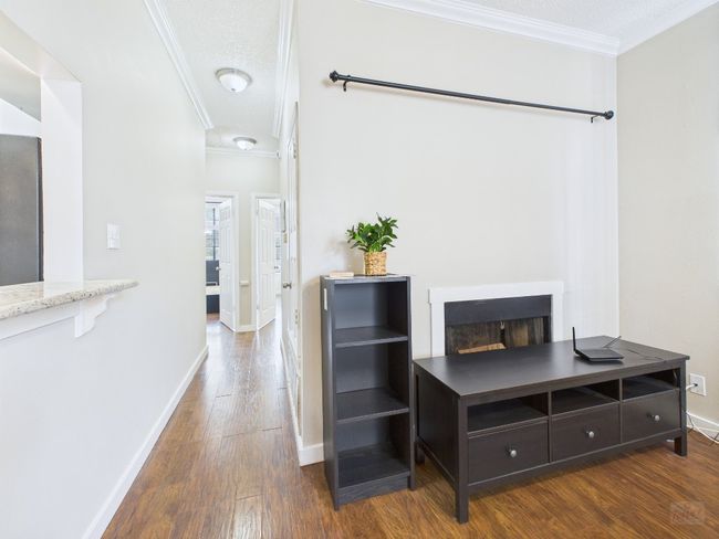 Corridor with ornamental molding, wood finished floors, and a textured ceiling | Image 14