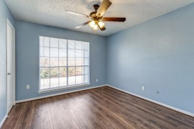 Empty room featuring wood finished floors, a textured ceiling, and a ceiling fan | Image 11