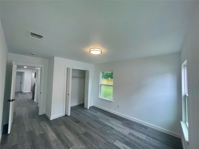 Unfurnished bedroom with dark wood finished floors and a closet | Image 7
