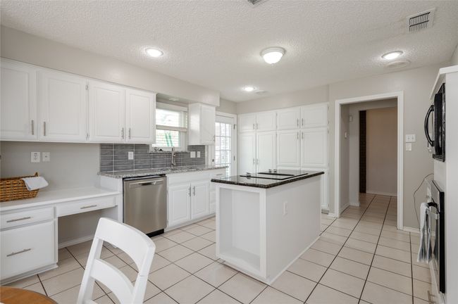 Kitchen with light tile patterned floors, visible vents, appliances with stainless steel finishes, white cabinetry, and a sink | Image 15