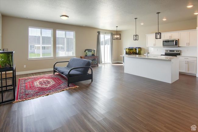 Kitchen with dark wood-style flooring, light countertops, white cabinetry, and stainless steel appliances | Image 6