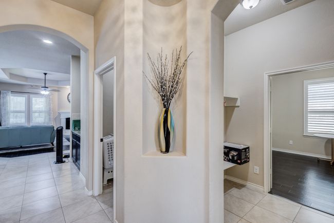 Hall featuring arched walkways, tile patterned floors, baseboards, and a raised ceiling | Image 5