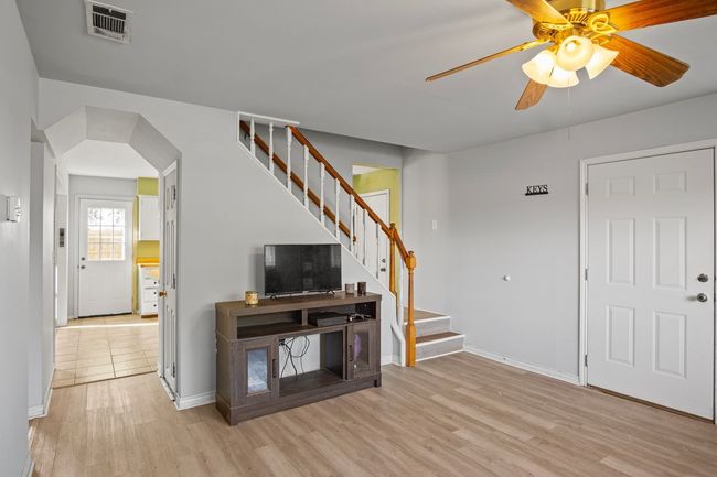 Living room with stairs, wood finished floors, and ceiling fan | Image 13