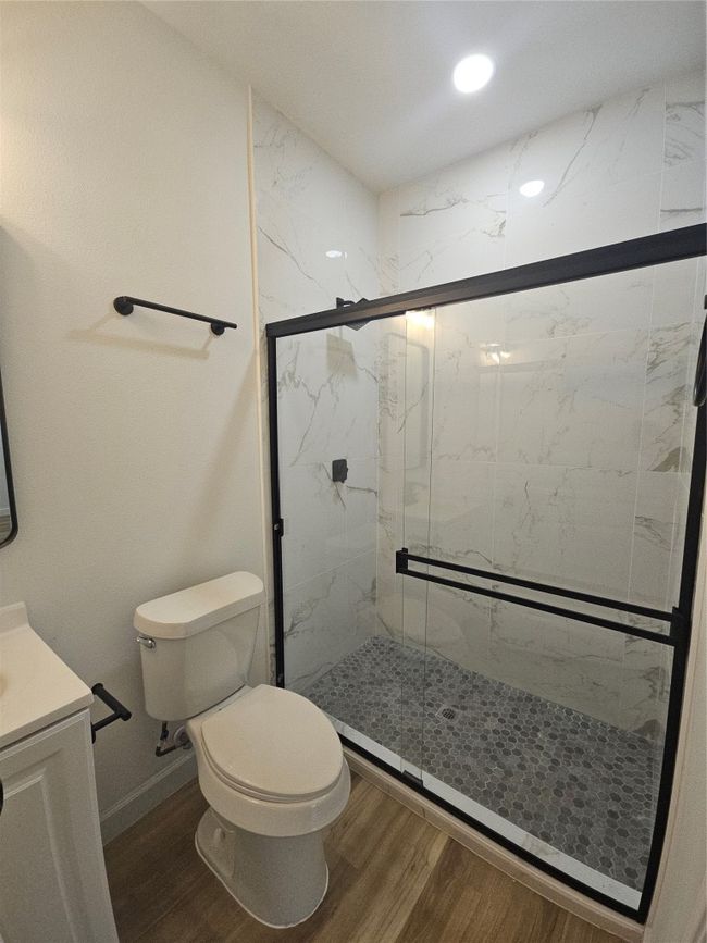 Bathroom with vanity, wood finished floors, baseboards, a marble finish shower, and toilet | Image 10