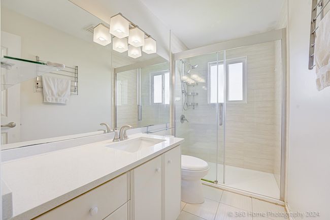 Bathroom with tile patterned floors, vanity, toilet, and a shower stall | Image 9