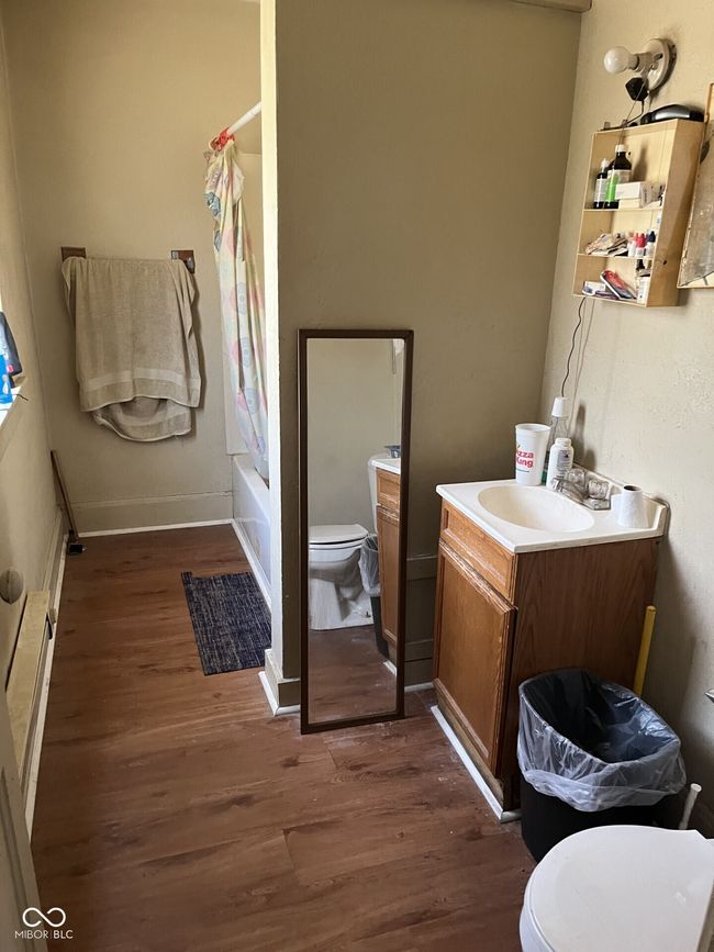bathroom featuring toilet, wood finished floors, shower / tub combo, and vanity | Image 9