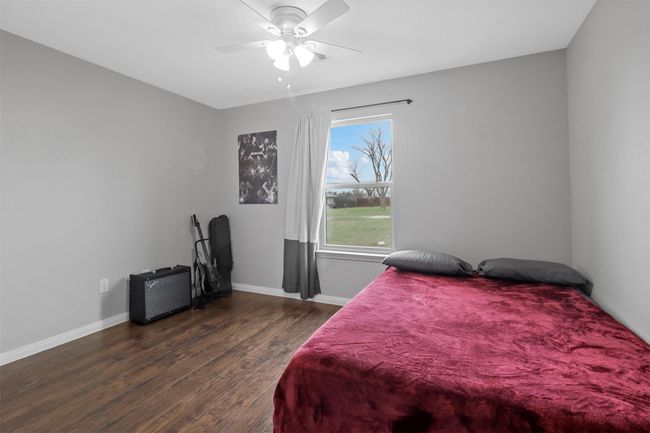 Bedroom with baseboards, wood finished floors, and a ceiling fan | Image 28