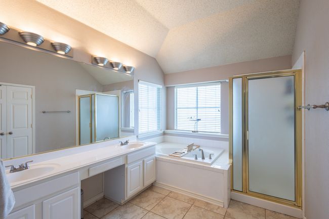 Bathroom with a shower stall, a bath, double vanity, vaulted ceiling, and tile patterned floors | Image 9