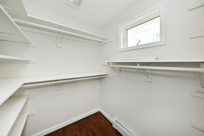 Walk in closet featuring dark wood finished floors and a baseboard radiator | Image 26
