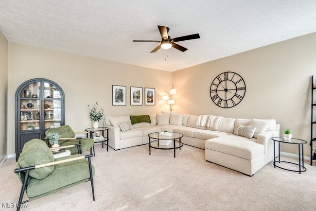 Carpeted living room featuring a ceiling fan and baseboards | Image 16
