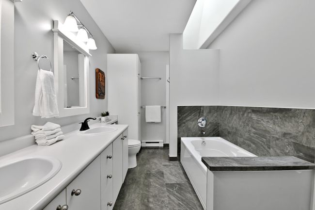 Full bathroom featuring toilet, a baseboard radiator, double vanity, and a sink | Image 27