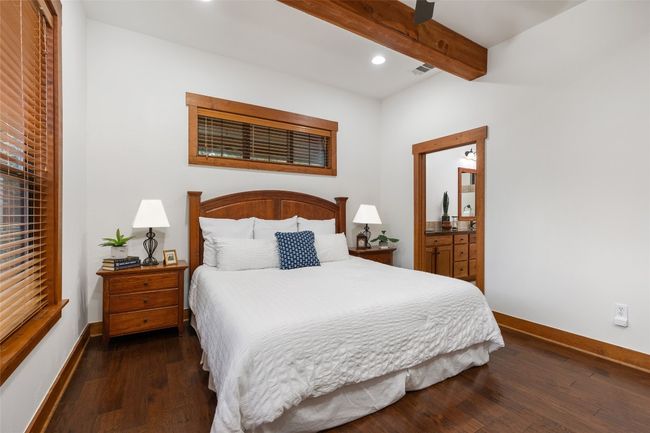 The primary bedroom is designed for comfort with access to the ensuite bath. The hand-scraped wood flooring, wood door & window frames continues throughout the home. | Image 13