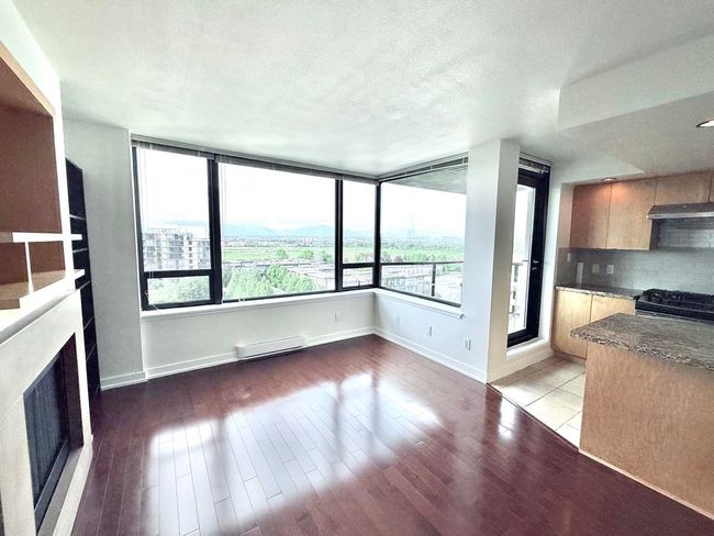 Unfurnished living room featuring a fireplace, wood finished floors, a baseboard heating unit, and a textured ceiling | Image 8