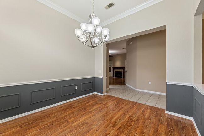 Spare room with ornamental molding, a chandelier, light wood finished floors, and a wainscoted wall | Image 13