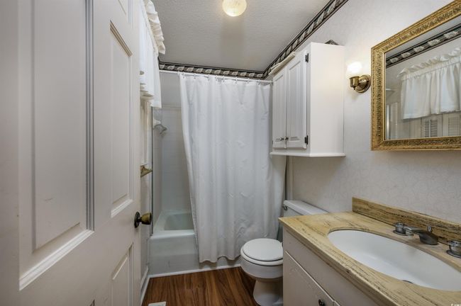 Full bathroom featuring shower / tub combo, hardwood / wood-style flooring, toilet, a textured ceiling, and vanity | Image 23